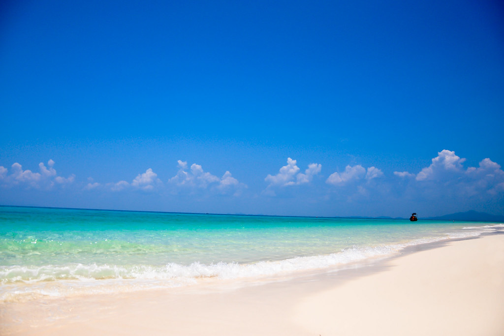 A quiet stretch of soft white sand under a clear blue sky in Phuket