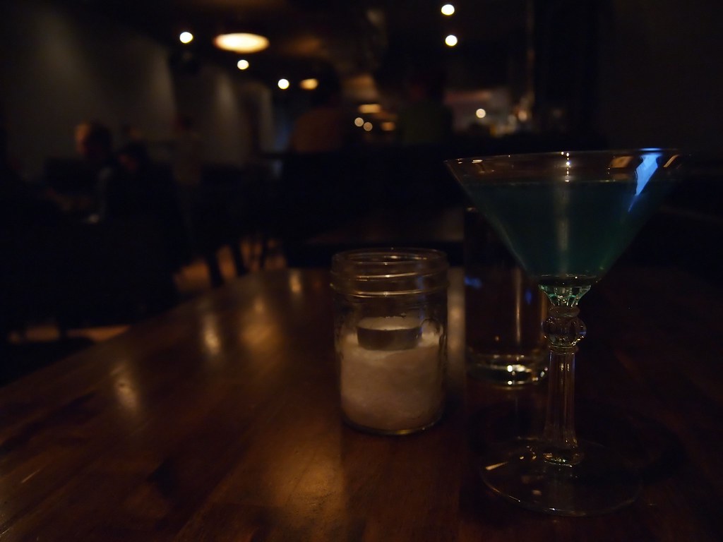 A cocktail glass glowing in a moody, low-lit Phuket bar