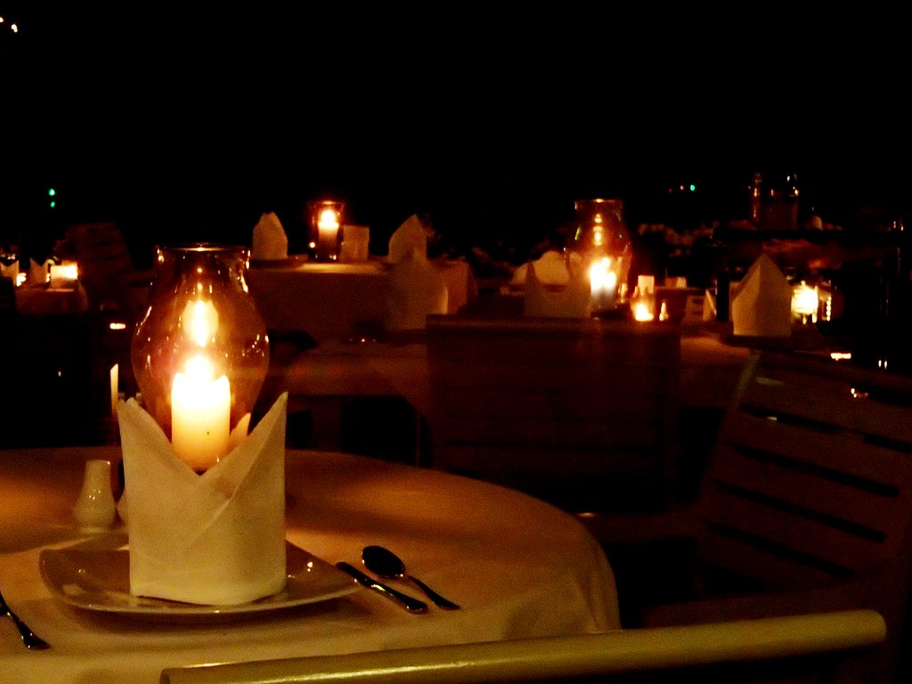 A single candle lantern glowing on a set dinner table, ready for a romantic evening in Phuket
