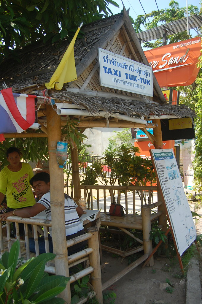 A taxi and tuk-tuk stand on a street in Phuket