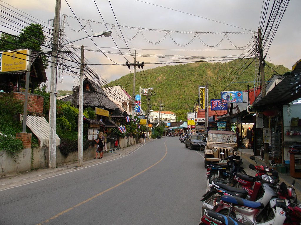 Kata town street at dusk with string lights, small bars and shopfronts