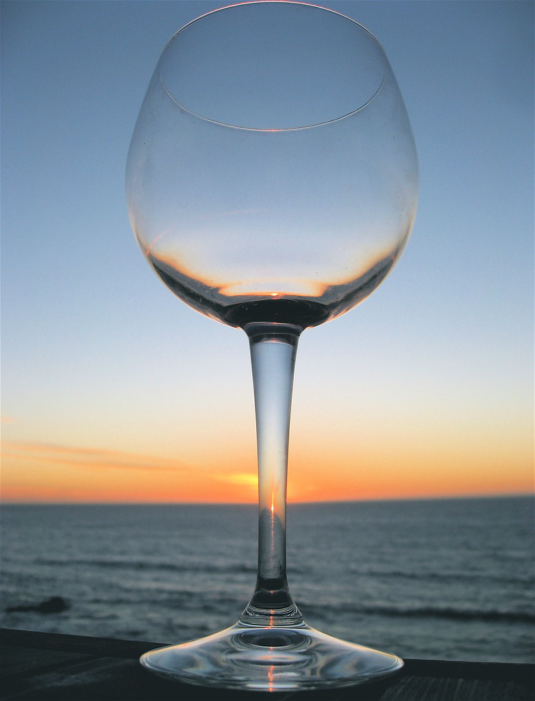 A glass of wine held up against a Phuket sunset