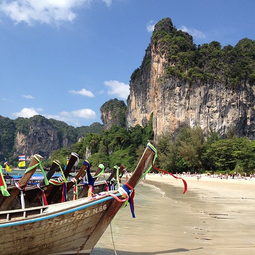 Longtail boats on a Krabi beach beneath towering karst cliffs