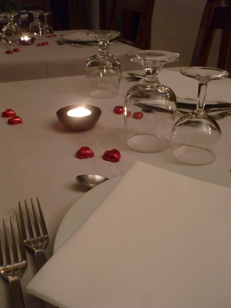 A candlelit table set with wine and rose petals for a special evening
