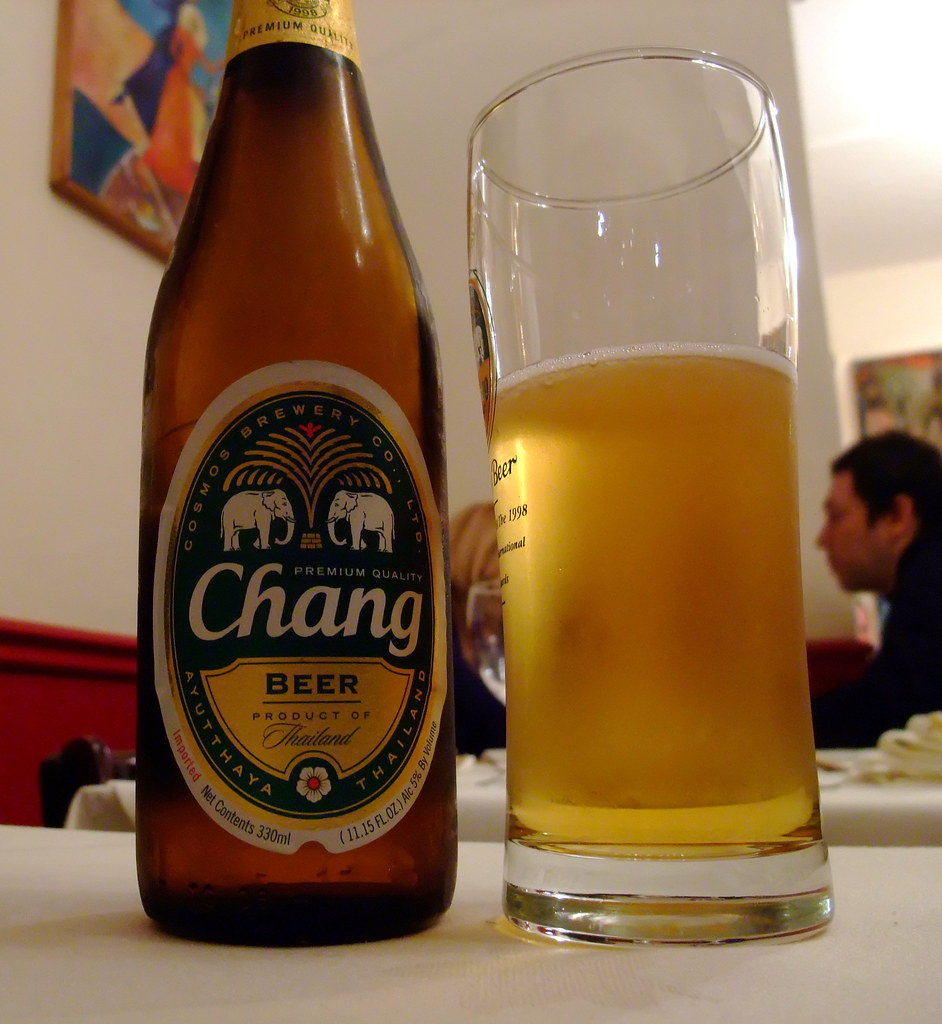 Bottle of Chang beer from Thailand next to a full glass on a table